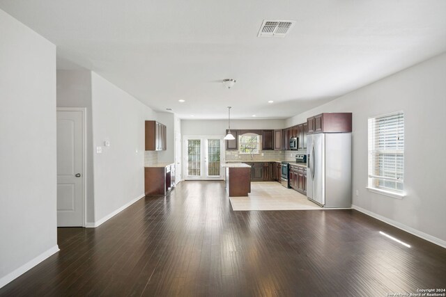 kitchen featuring hardwood / wood-style flooring, appliances with stainless steel finishes, tasteful backsplash, a center island, and pendant lighting