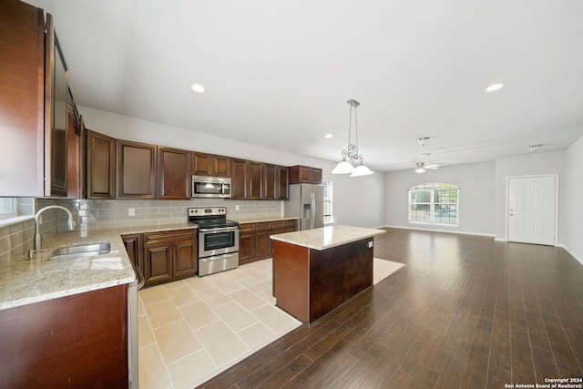 kitchen featuring light hardwood / wood-style floors, sink, appliances with stainless steel finishes, hanging light fixtures, and a center island