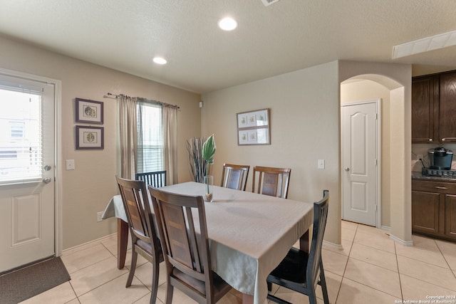 dining space with a textured ceiling, plenty of natural light, and light tile patterned flooring