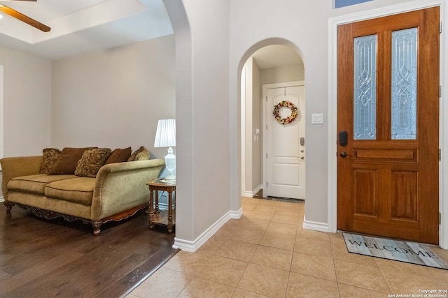 tiled foyer featuring ceiling fan and a raised ceiling