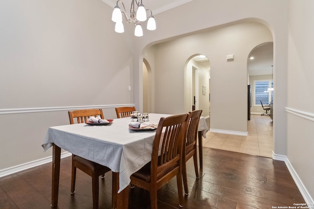 dining area featuring dark hardwood / wood-style flooring, ornamental molding, and a notable chandelier