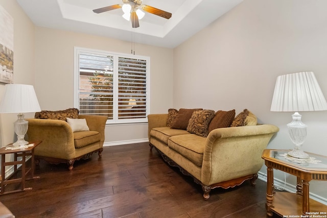 living room with ceiling fan, dark hardwood / wood-style flooring, and a raised ceiling