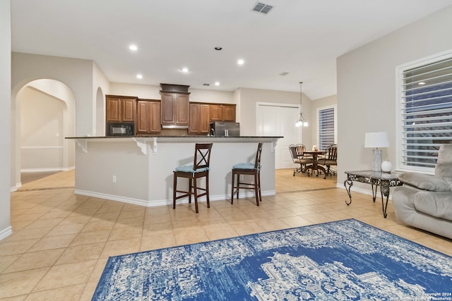 kitchen featuring a kitchen breakfast bar, light tile patterned floors, and stainless steel refrigerator