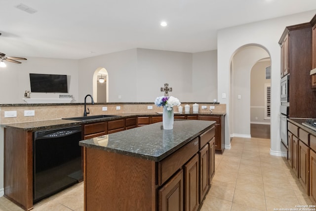 kitchen featuring dark stone counters, appliances with stainless steel finishes, sink, and a center island