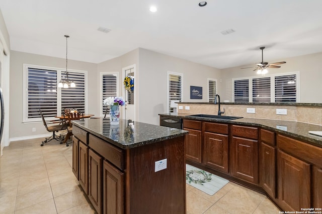 kitchen with hanging light fixtures, light tile patterned floors, sink, and a center island