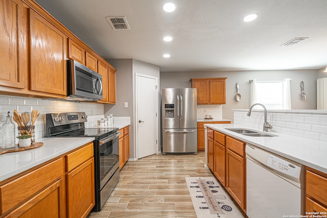 kitchen with decorative backsplash, sink, stainless steel appliances, and light wood-type flooring