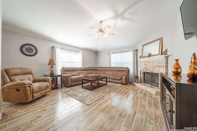 living room with a wealth of natural light, a fireplace, ceiling fan, and lofted ceiling