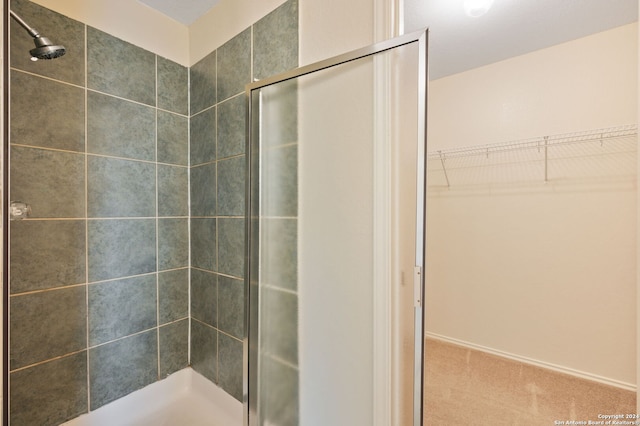 full bathroom featuring a shower stall and a walk in closet
