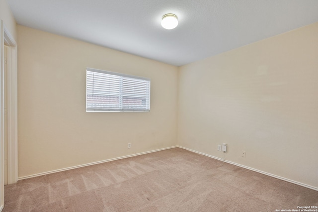 carpeted empty room featuring baseboards