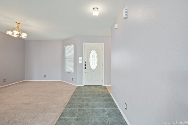 foyer with dark colored carpet and a chandelier