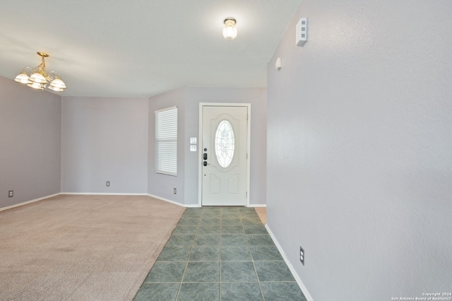 carpeted entrance foyer with a chandelier and baseboards