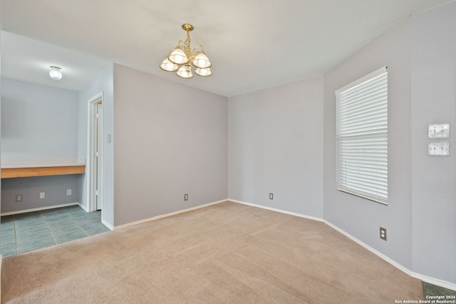 carpeted empty room with an inviting chandelier