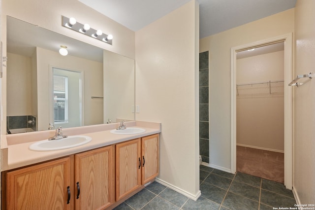 bathroom featuring a spacious closet, double vanity, tile patterned flooring, and baseboards