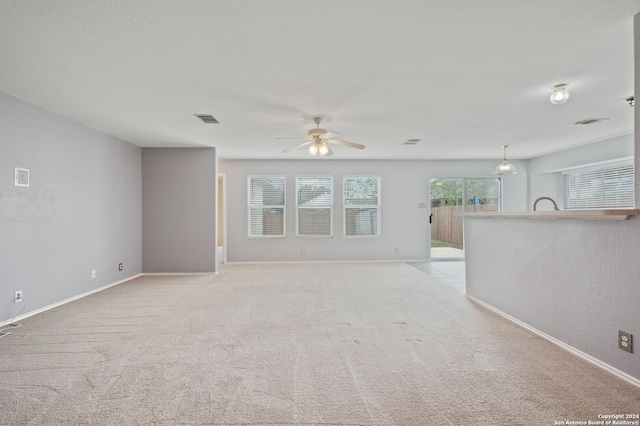 unfurnished living room with ceiling fan, baseboards, and light carpet