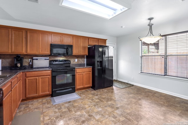 kitchen featuring pendant lighting, black appliances, sink, and tasteful backsplash