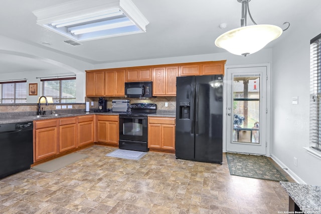 kitchen with sink, black appliances, decorative light fixtures, and tasteful backsplash