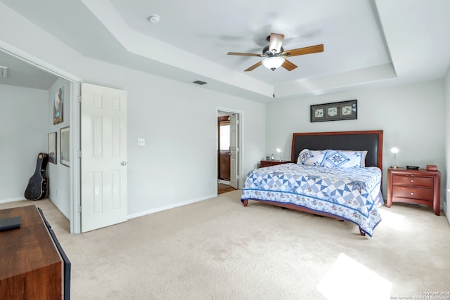 bedroom featuring ceiling fan, light carpet, and a raised ceiling