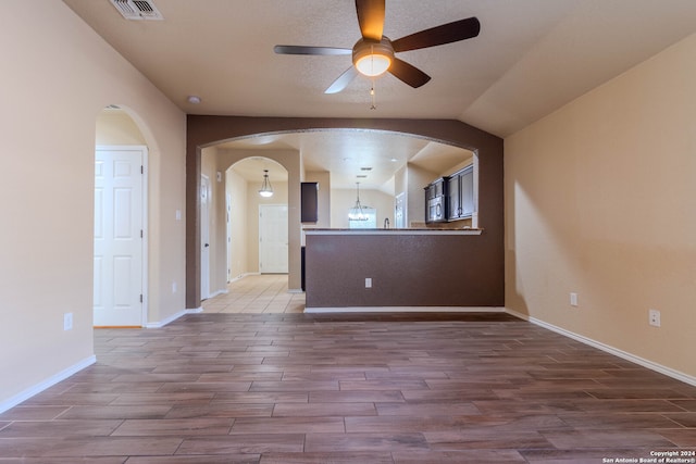 unfurnished room featuring ceiling fan, wood-type flooring, a textured ceiling, and vaulted ceiling