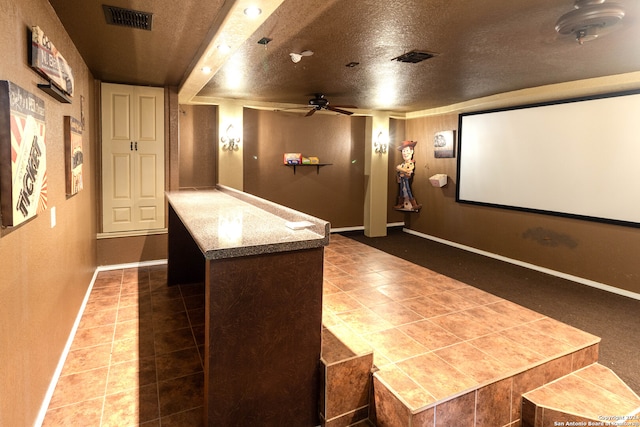 home theater room featuring tile patterned flooring, a textured ceiling, and ceiling fan