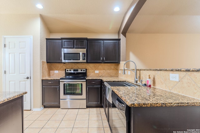 kitchen with backsplash, stone counters, sink, appliances with stainless steel finishes, and light tile patterned flooring