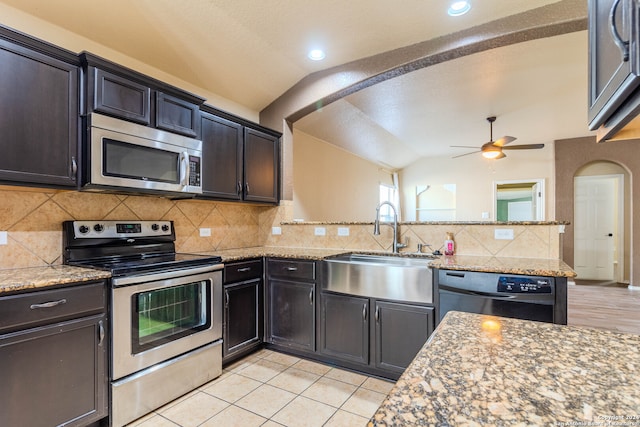 kitchen featuring light stone countertops, sink, backsplash, lofted ceiling, and appliances with stainless steel finishes