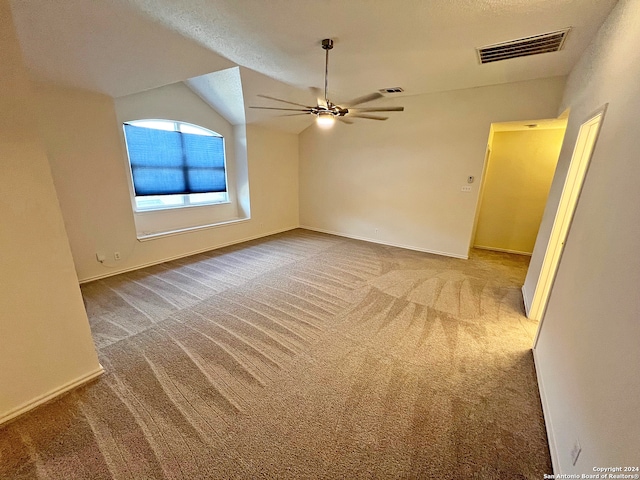 carpeted spare room with lofted ceiling, a textured ceiling, and ceiling fan