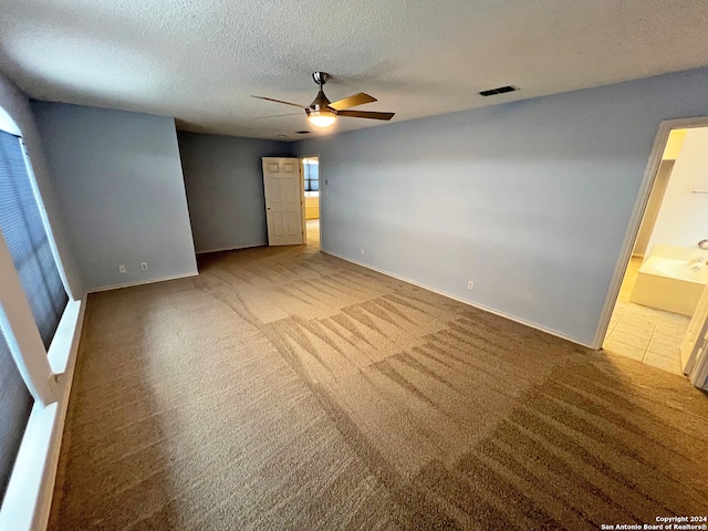 unfurnished bedroom featuring ensuite bathroom, a textured ceiling, carpet floors, and ceiling fan