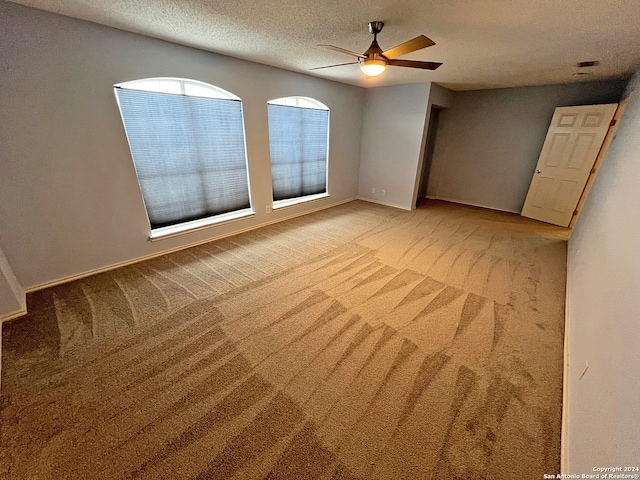 carpeted spare room with a textured ceiling and ceiling fan