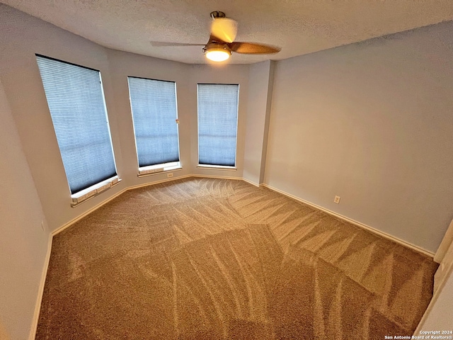 carpeted spare room featuring ceiling fan and a textured ceiling