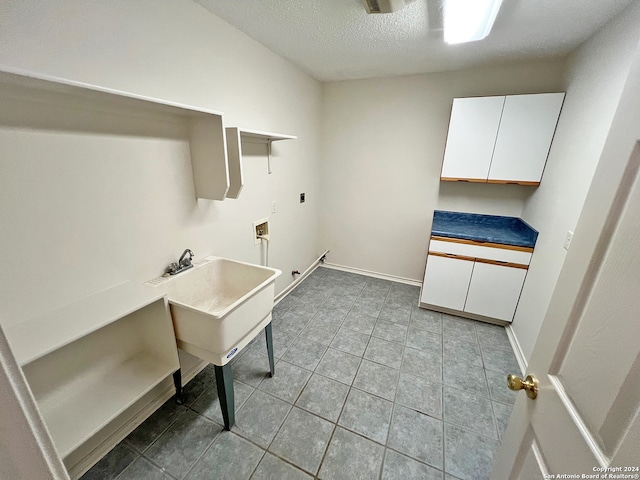 laundry area featuring hookup for an electric dryer, cabinets, a textured ceiling, light tile patterned floors, and hookup for a washing machine