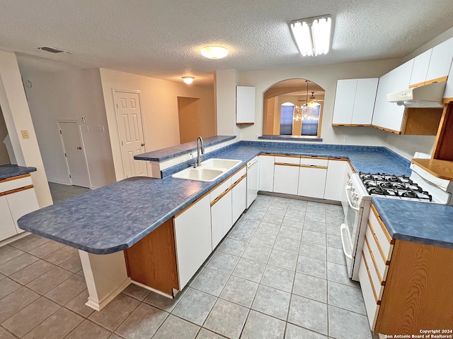 kitchen with sink, kitchen peninsula, a textured ceiling, white appliances, and white cabinets