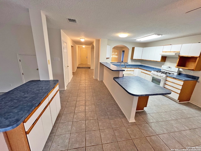 kitchen with white cabinets, white gas stove, a textured ceiling, and light tile patterned floors