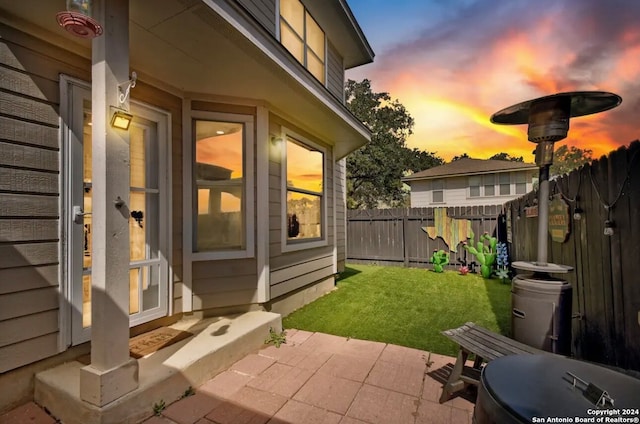 patio terrace at dusk featuring a lawn