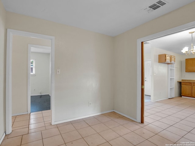 tiled empty room with a notable chandelier