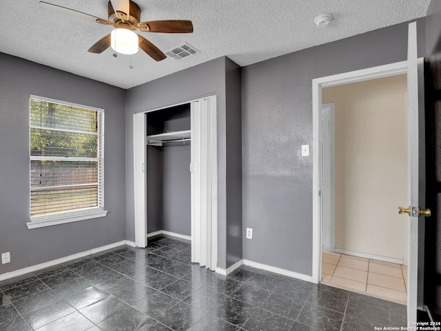 unfurnished bedroom featuring ceiling fan, a textured ceiling, and a closet