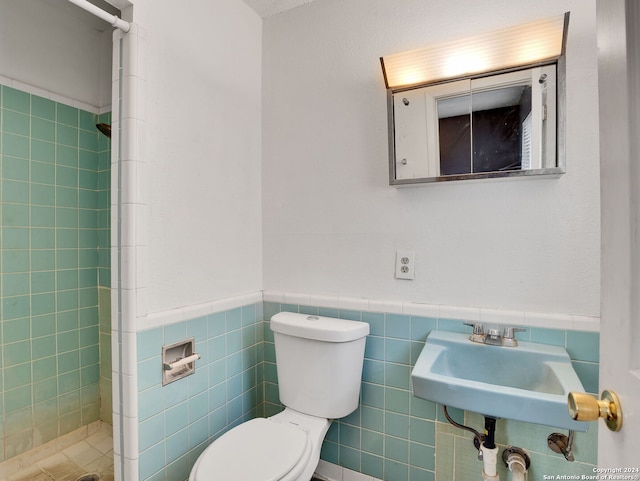 bathroom featuring a shower, toilet, tile walls, and sink