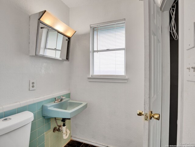 bathroom featuring tile walls, sink, and toilet