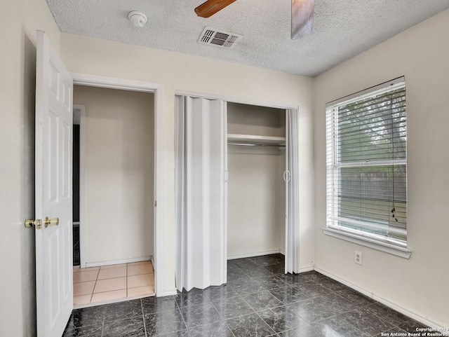 unfurnished bedroom with a closet, a textured ceiling, and ceiling fan