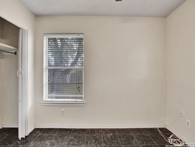 unfurnished bedroom featuring multiple windows, a closet, and a textured ceiling