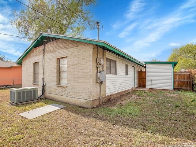 view of side of property featuring cooling unit and a lawn