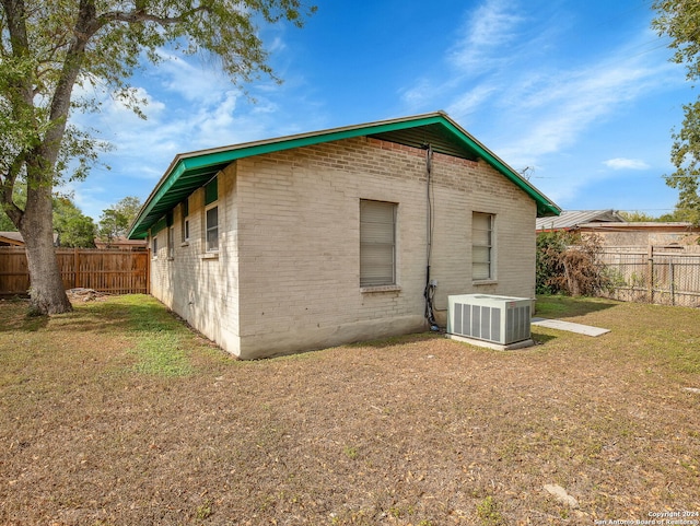 rear view of property featuring central AC and a lawn