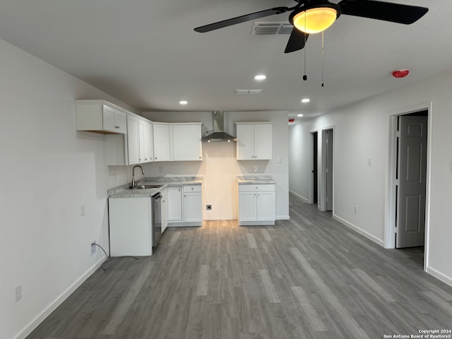 kitchen featuring light hardwood / wood-style floors, sink, stainless steel dishwasher, wall chimney range hood, and white cabinetry