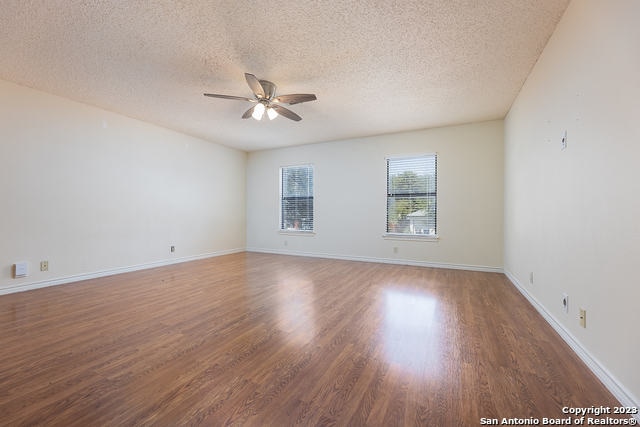 empty room with ceiling fan, a textured ceiling, and dark hardwood / wood-style floors