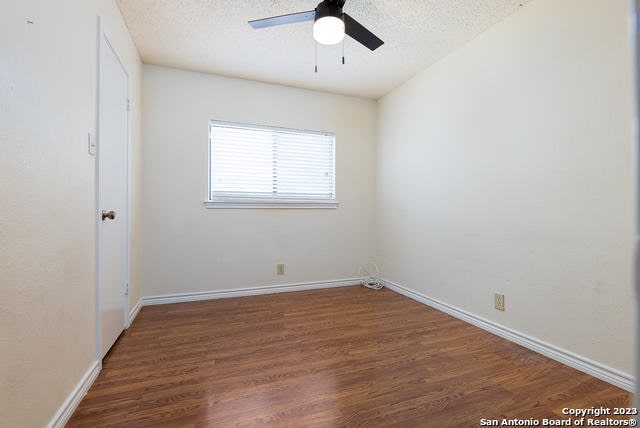 empty room featuring ceiling fan, a textured ceiling, and dark hardwood / wood-style floors