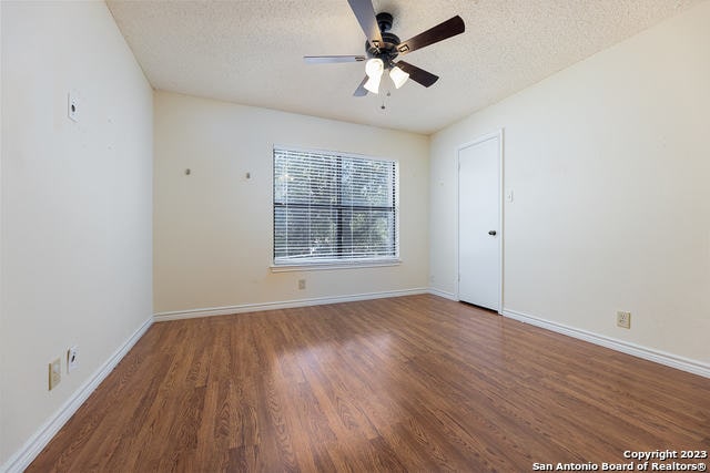 unfurnished room with ceiling fan, dark hardwood / wood-style floors, and a textured ceiling