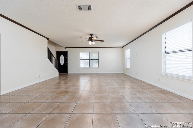 tiled spare room with a textured ceiling, ceiling fan, and crown molding