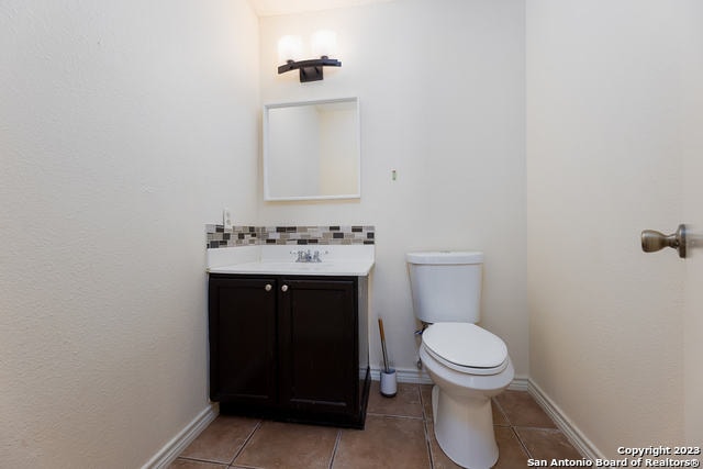 bathroom with toilet, vanity, and tile patterned flooring