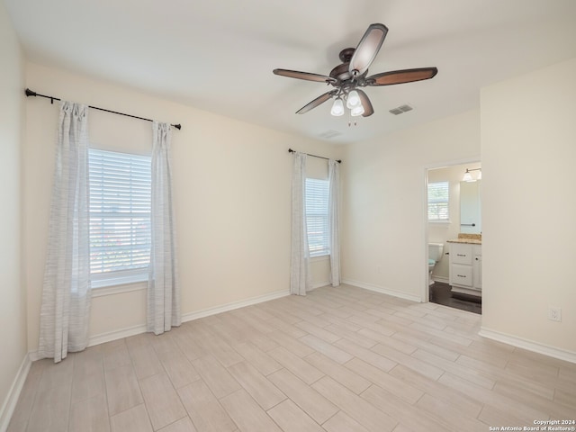 unfurnished bedroom with connected bathroom, multiple windows, ceiling fan, and light hardwood / wood-style floors