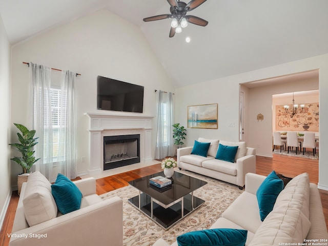 living room with hardwood / wood-style flooring, ceiling fan with notable chandelier, and high vaulted ceiling