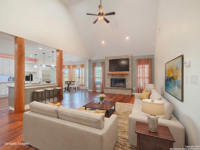 living room with a stone fireplace, high vaulted ceiling, hardwood / wood-style flooring, and ceiling fan